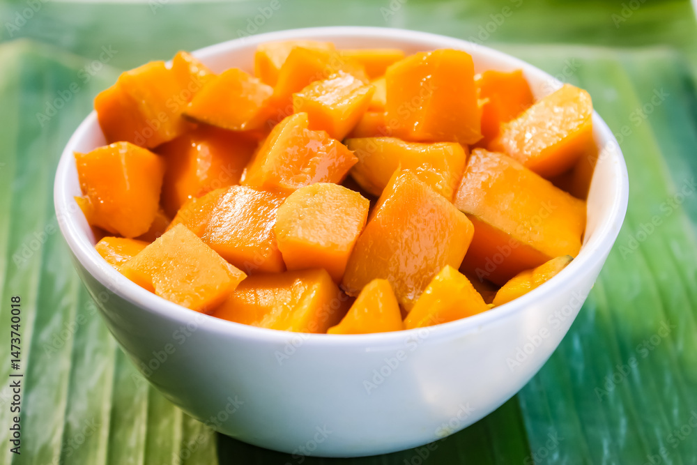 a bowl of cut mangoes on a banana leaf background.tropical fruit. a bowl of cut mangoes on a banana leaf background.tropical fruit.