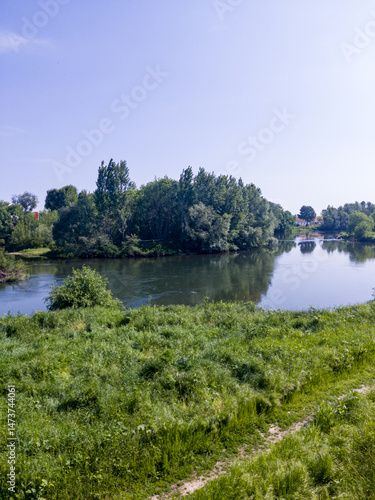 Obraz na płótnie Landscape with grass field, river and blue sky w salonie