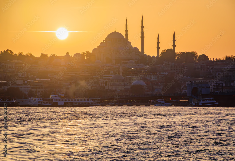 Fototapeta premium Sunset cityscape of the Historic Peninsula area across Bosphorus Strait by Galata Bridge with the Yeni Cami and Suleymaniye Mosques, Istanbul, Turkey