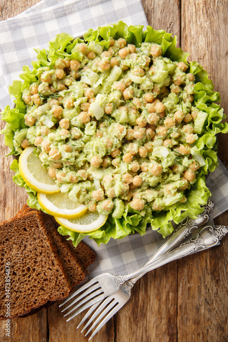 Diet protein salad with chickpeas, mashed avocado, onion and celery served with whole grain bread close-up in a plate on the table. Vertical top view from above