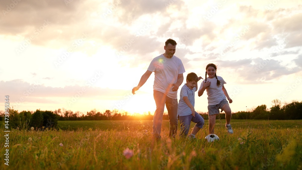 Fototapeta premium Father daughter, son playing football at sunset summer meadow slow motion. Happy active family kicking ball soccer teaching game having fun nature field kids enjoy weekend leisure together. Dad, kids