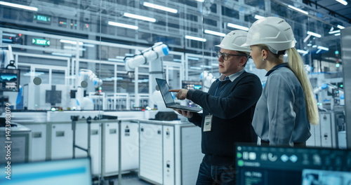 Fotografie Female and Male Industrial Engineers Monitoring and Analyzing Conditions at a Mo
