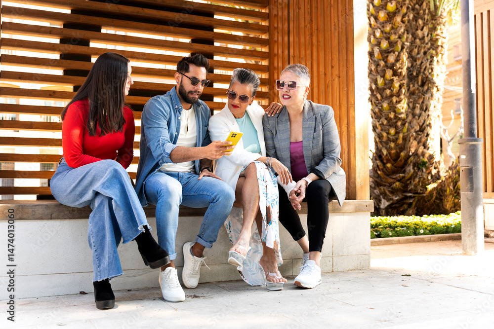 Fototapeta premium Group of diverse friends sharing a moment of connection while using a smartphone outdoors