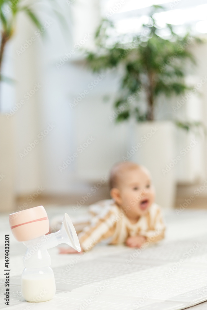 Fototapeta premium Electric breast pump with baby in background. Baby care concept.