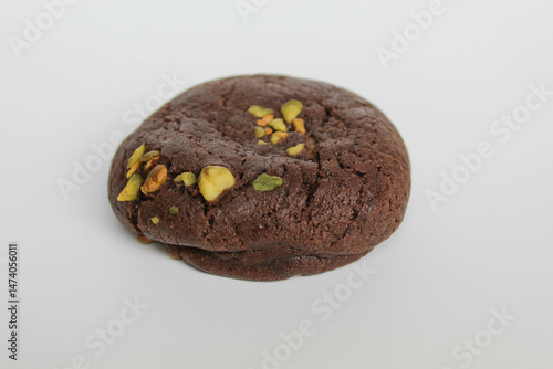 A chocolate soft cookie, with green pistachio topping, isolated on white background