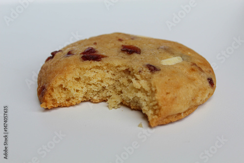 A bitten white choco soft cookie with almond and berry cuts, isolated on white background