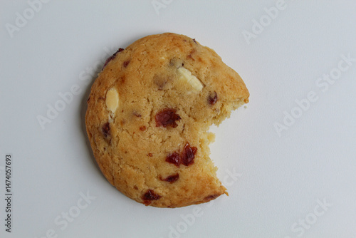 A bitten white choco soft cookie with almond and berry cuts, isolated on white background