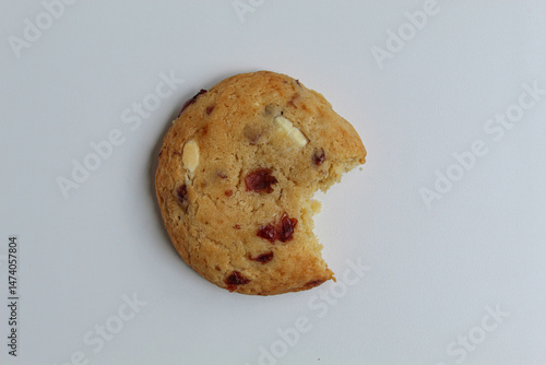 A bitten white choco soft cookie with almond and berry cuts, isolated on white background