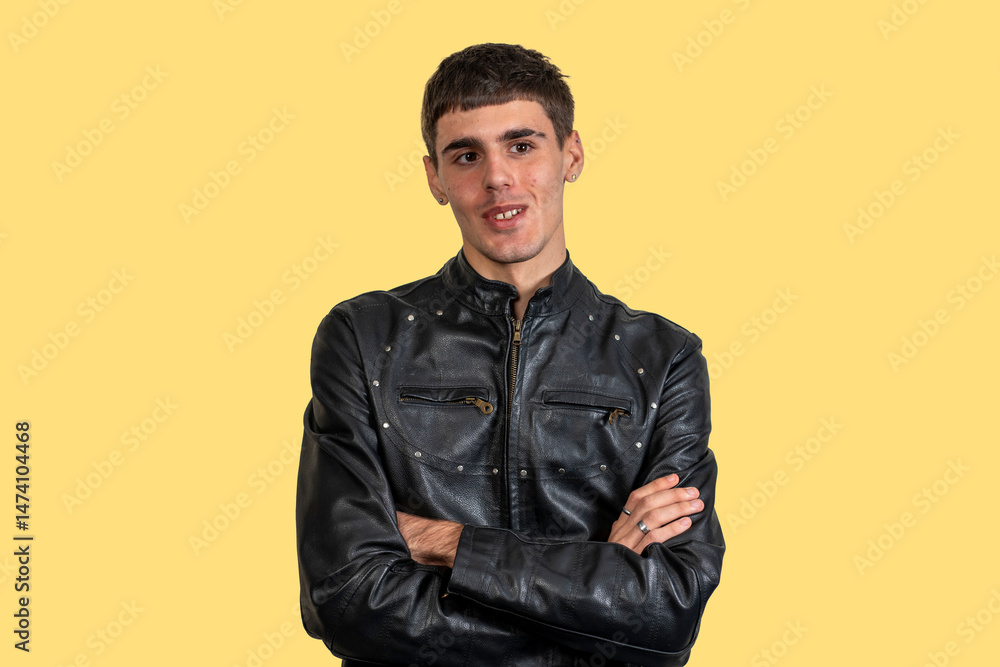 Fototapeta premium Young man wearing black leather jacket with crossed arms on yellow background