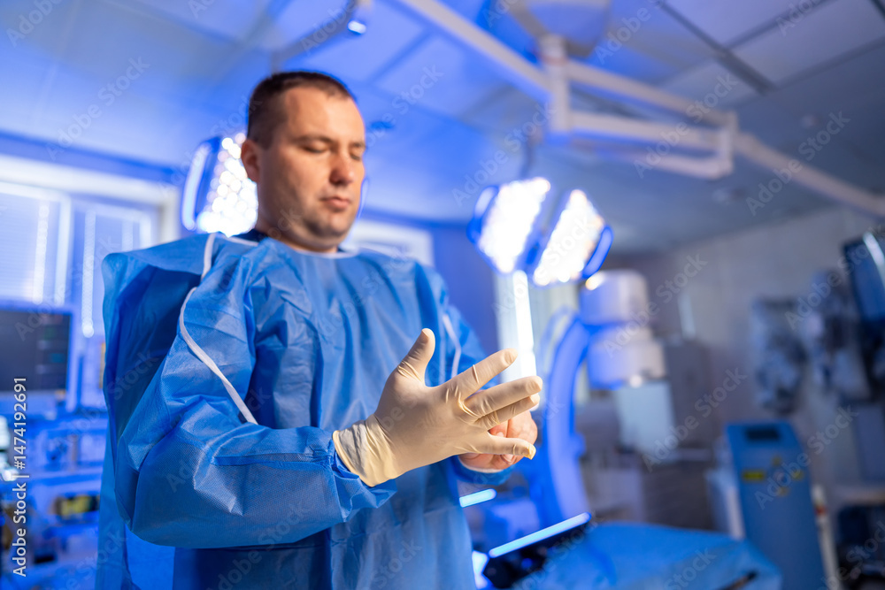 Surgeon readies for surgery. A medical professional dons surgical gloves while preparing for a procedure in a well-lit operating room. Surgeon readies for surgery. A medical professional dons surgical gloves while preparing for a procedure in a well-lit operating room.