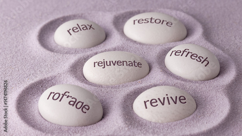 Five smooth, off-white stones rest in purple sand, each inscribed with word related to rejuvenation and relaxation: relax, restore, refresh, rejuvenate, revive. Showcases wellness and serenity.