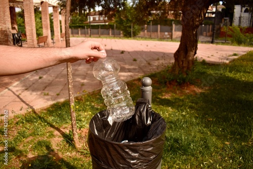 Eco-conscious action: man throws bottle into bin. Clean city and reduce pollution message.

