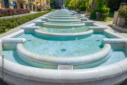 Frontal view of the ancient fountain with healthy thermal water in the city of Acqui Terme, Piedmont, Italy. The water flows through several steps made of marble.