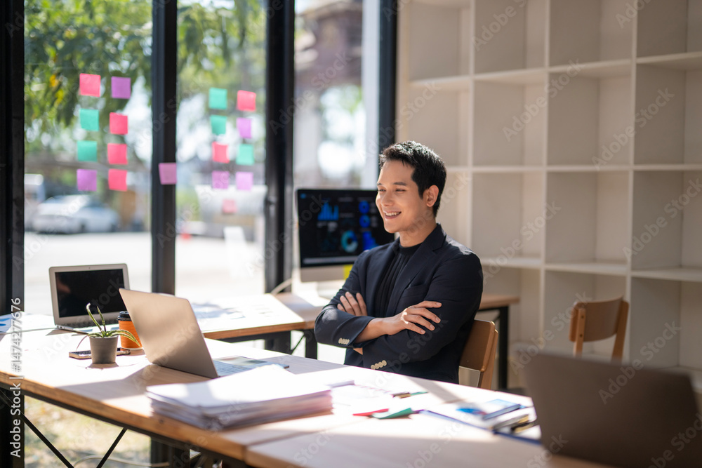 Fototapeta premium A man is sitting at a desk with a laptop and a computer monitor