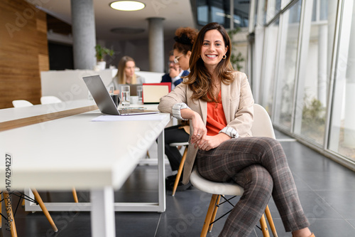 Bild auf Leinwand Portrait of confident businesswoman with laptop at table sitting in board room w