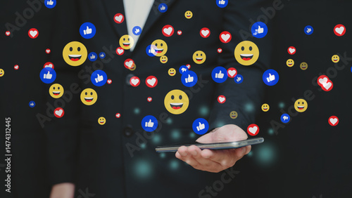 Fotografie Businessman using smartphone with social media reaction icons floating