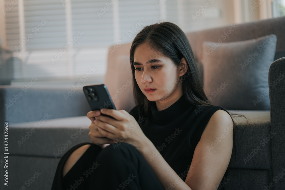 Depressed and unhappy Asian woman sits with anxiety on the sofa in her living room at home. Depressed and unhappy Asian woman sits with anxiety on the sofa in her living room at home.