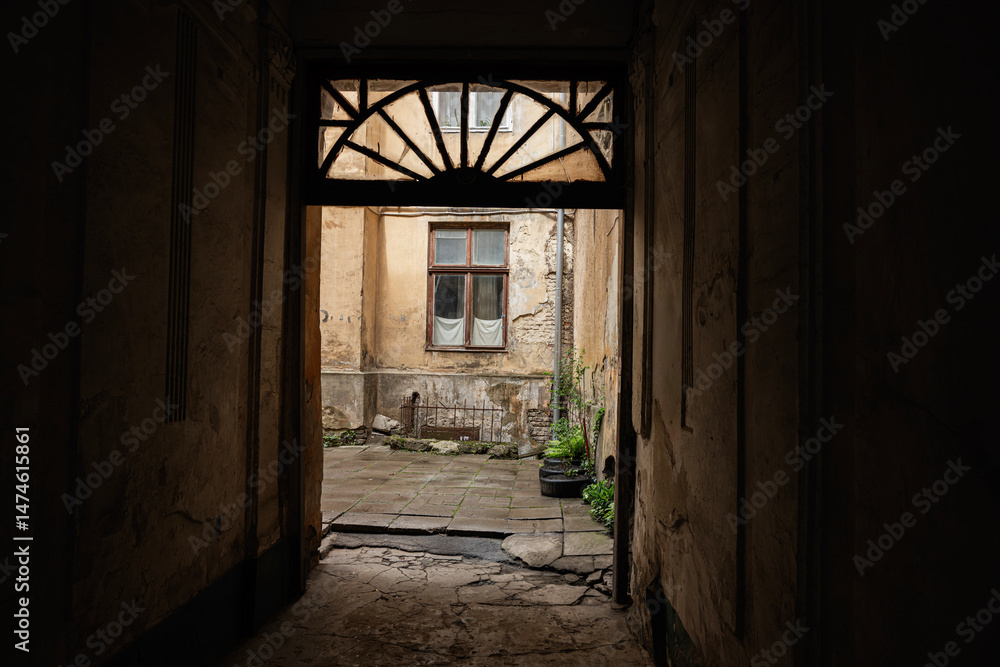 Old courtyard viewed through a dark arched passage with weathered textures Old courtyard viewed through a dark arched passage with weathered textures