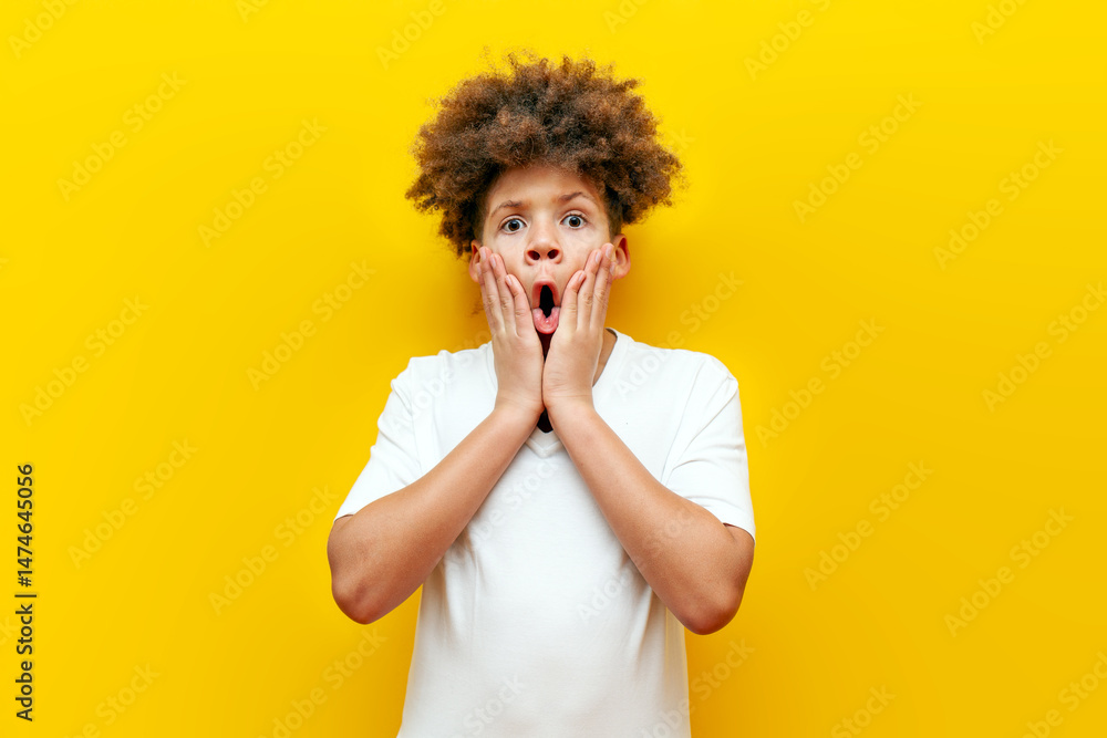shocked curly african american boy looking at camera in amazement over yellow isolated background, surprised teenager in white t-shirt shocked curly african american boy looking at camera in amazement over yellow isolated background, surprised teenager in white t-shirt