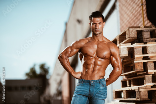 Shirtless muscular young man in jeans standing on the street