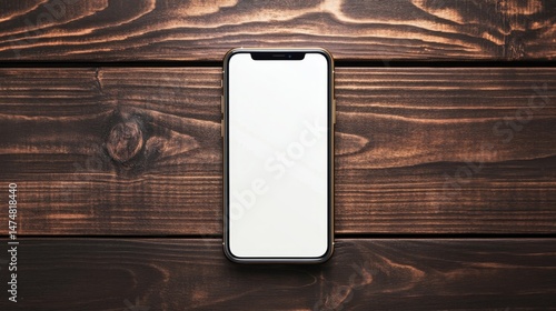 Smartphone with blank screen on dark wooden table, top view flat lay photo.