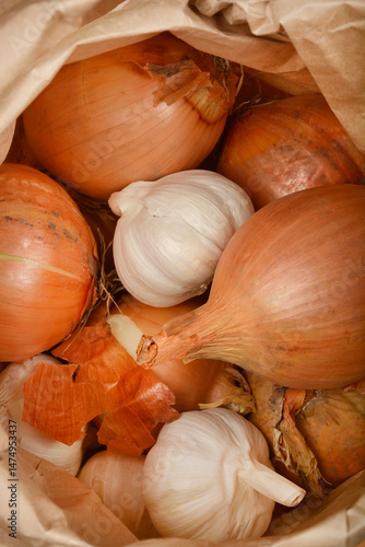 Obraz na płótnie A close-up from inside a paper bag shows several brown onions and white garlic bulbs mixed together w salonie