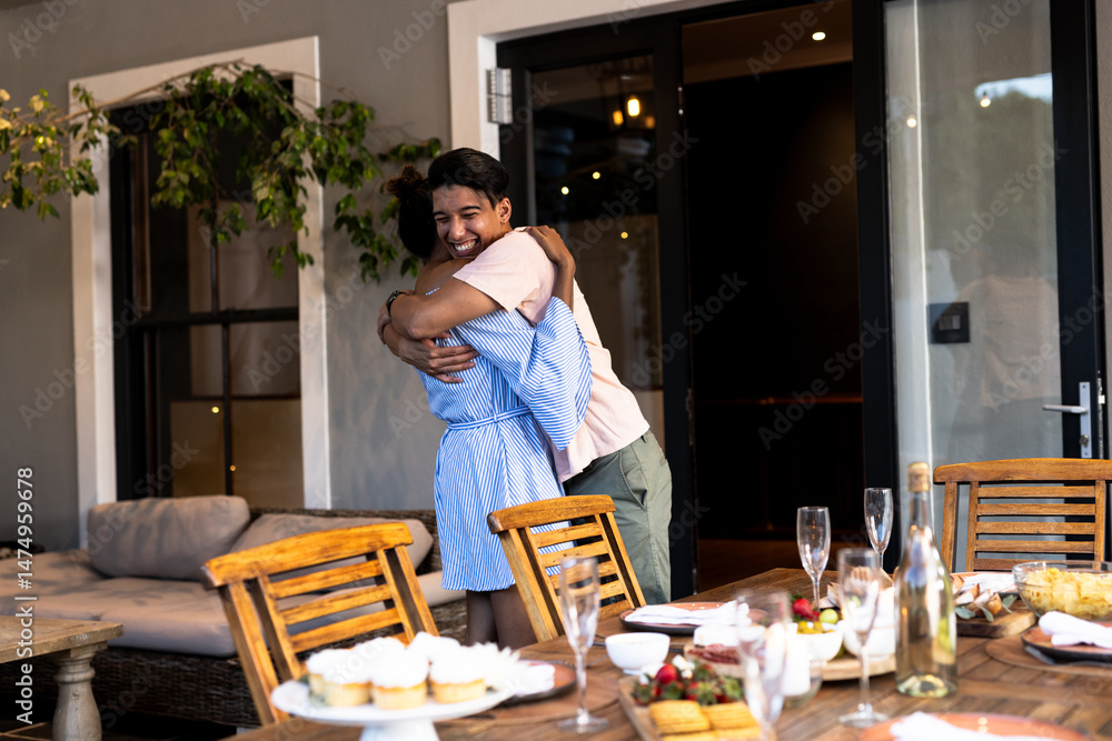 Fototapeta premium Diverse friends hugging joyfully at outdoor gathering with cupcakes and champagne on table