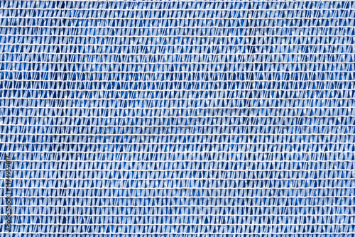 Obraz na płótnie A close-up shows a textured white plastic netting laid over a blue surface, creating a striped pattern w salonie