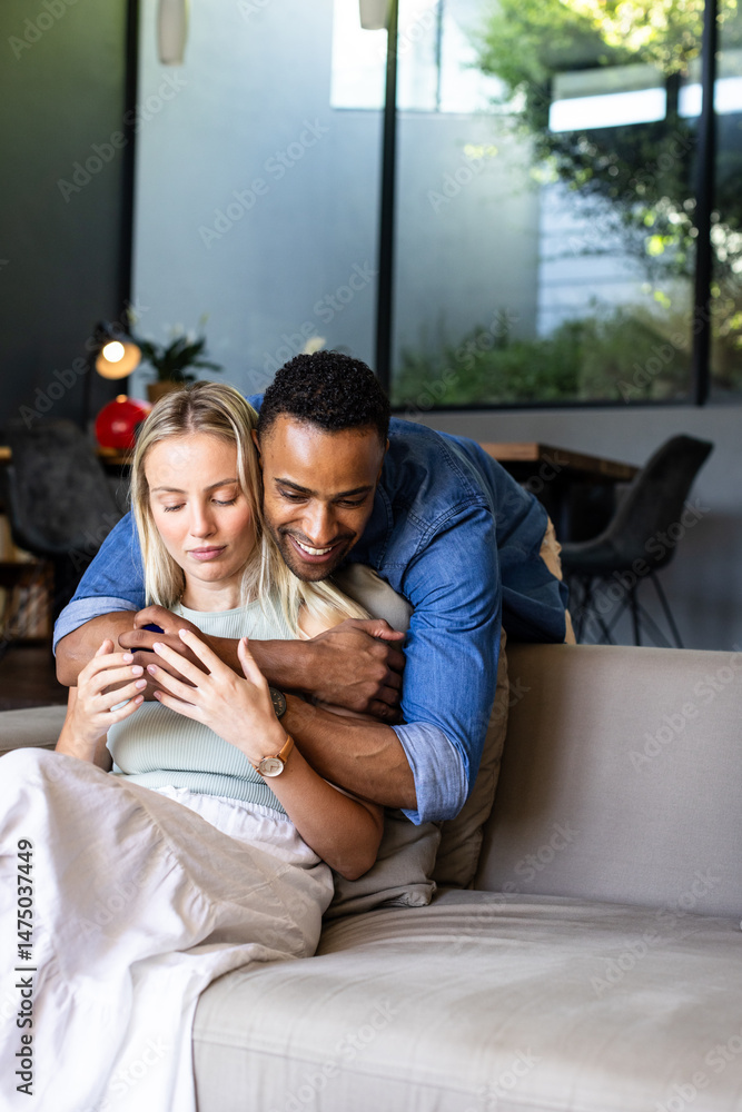Obraz premium Couple embracing on sofa at home, enjoying peaceful and loving moment together