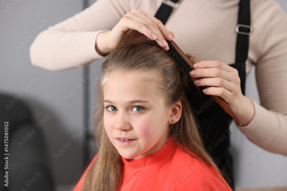 Naklejka premium Hairdresser doing girl's hairstyle in salon, closeup