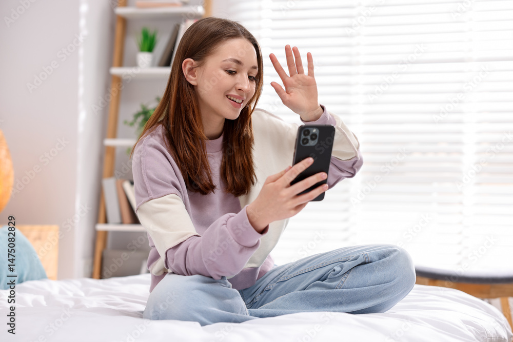 Teenage girl having video chat via smartphone on bed at home Teenage girl having video chat via smartphone on bed at home