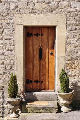 Wooden front door of a beautiful old stone cottage house on a street in an English village