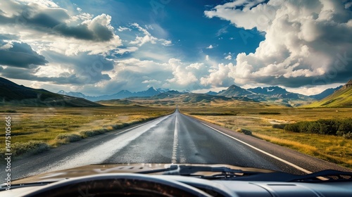 A road with a long stretch of highway in the distance. The sky is cloudy and the road is wet