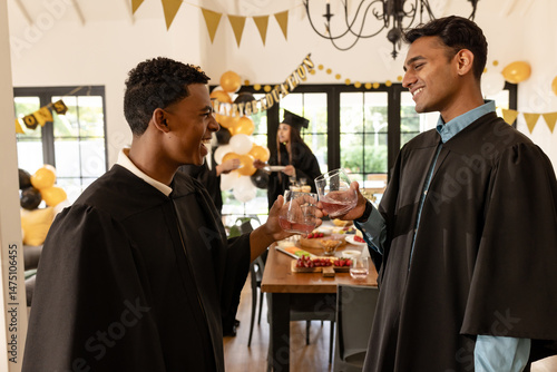 Photography Graduates in caps and gowns celebrating with drinks at home party