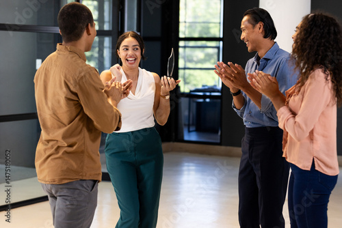 Business team celebrating colleague receiving award in modern office setting
