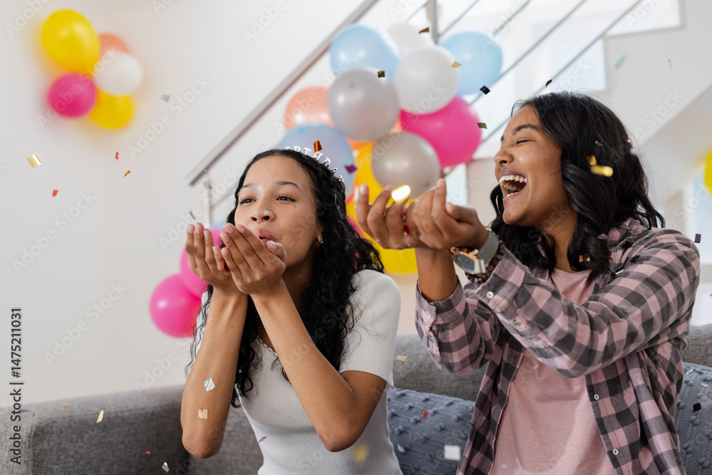 Fototapeta premium Celebrating at home, two women joyfully throwing confetti with colorful balloons