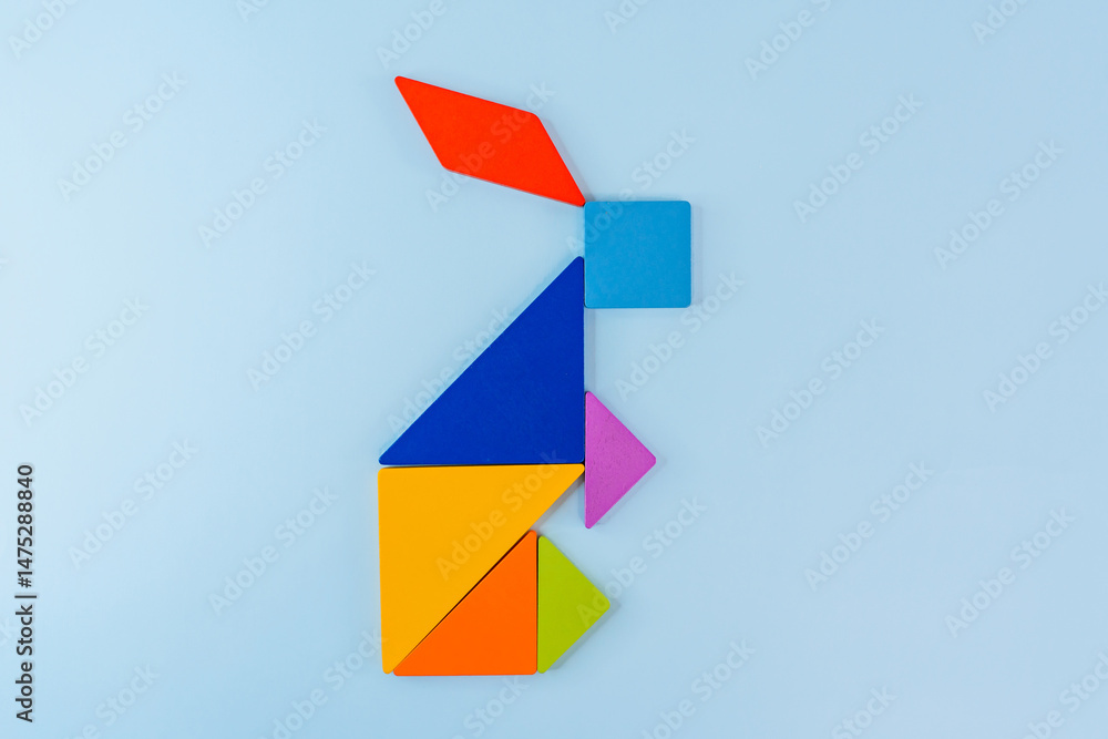 Tangram puzzle depicting a rabbit or a hare on a blue background, conceptual image, place for text