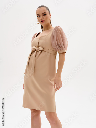 Pregnant girl model in stylish clothes on a colorless background in the studio.