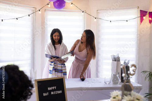 Fotografia Young girl reading from book during Bat Mitzvah celebration with supportive woma