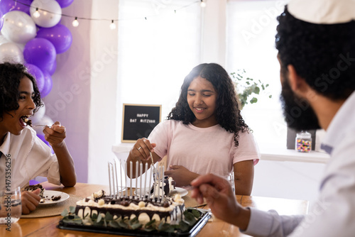 Photos Family celebrating Bat Mitzvah with cake, sharing joyful moments together at hom