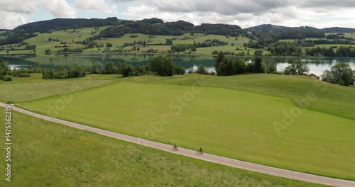 Two Friends Cycling Along Lake Irrsee, Austria – 4K Wide Drone Aerial Adventure Shot