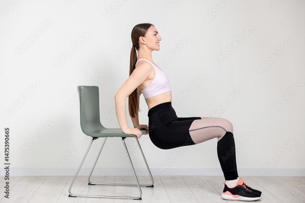 Fototapeta premium Beautiful woman exercising with chair at home