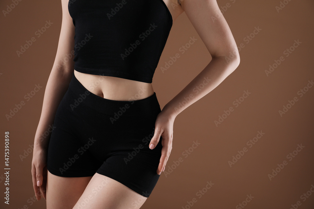 Fototapeta premium Attractive woman against brown background, closeup on belly
