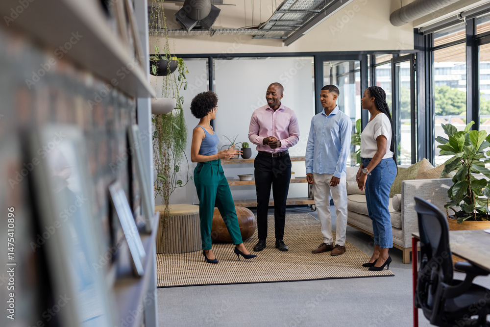 Fototapeta premium In office, professionals standing together discussing project with positive expressions