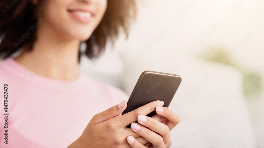 Online chat and app for shopping, education and blogging, ad and good offer. Happy young african american lady looks in phone and typing message in living room interior, panorama, free space, cropped Online chat and app for shopping, education and blogging, ad and good offer. Happy young african american lady looks in phone and typing message in living room interior, panorama, free space, cropped