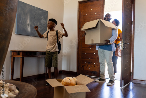 Family moving into new home, carrying boxes and feeling excited together