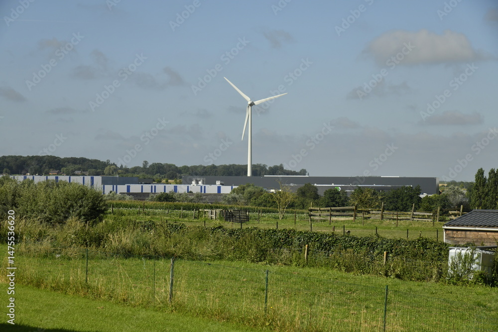 Fototapeta premium Éolienne se dressant haut dans le ciel au site industriel de Ghislenghien (Ath) 