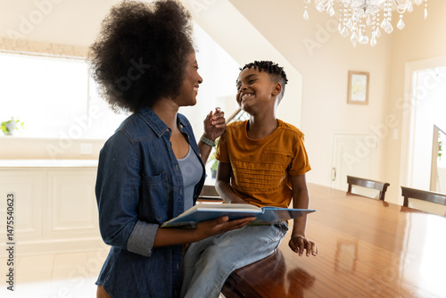 Mother reading book to smiling son at home, enjoying quality time together
