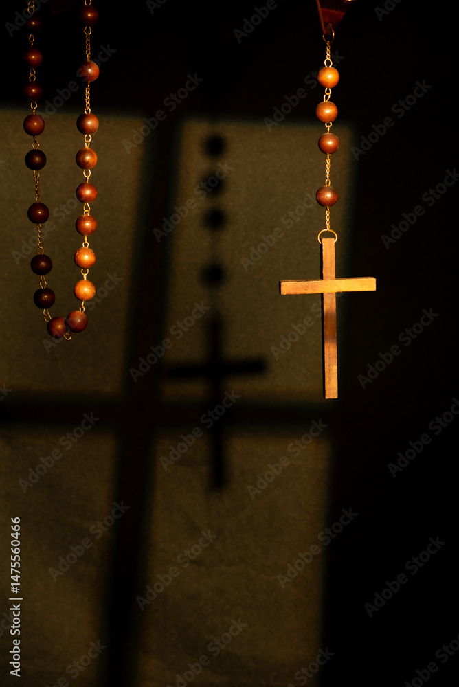 Wooden rosary, beautiful and large antique rosary under the light of a window and with a black background, selective focus.