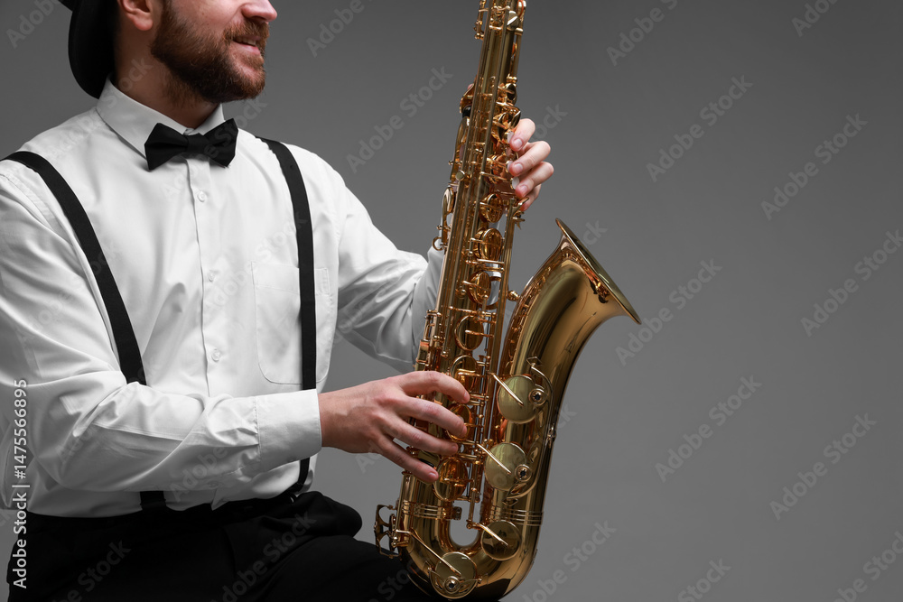 Naklejka premium Professional musician with saxophone on grey background, closeup. Space for text